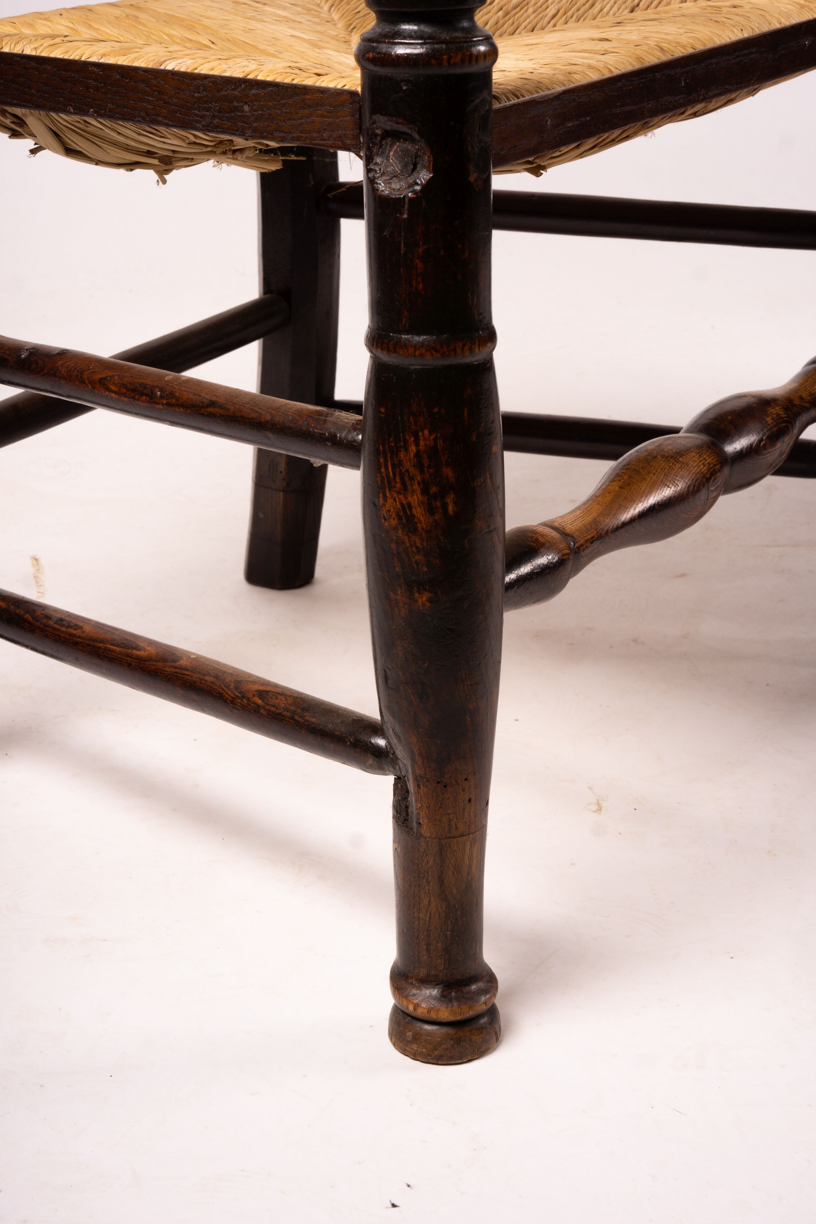 A pair of early 19th century Lancashire ash and fruitwood rush seat ladderback elbow chairs, width 60cm, depth 46cm, height 110cm